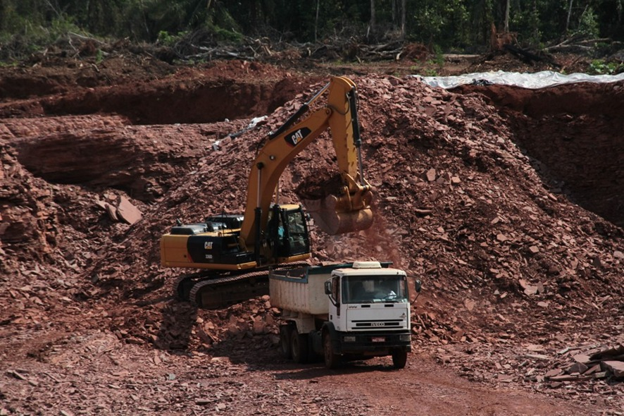 Máquina escavadeira opera em área de rejeitos em Ariquemes.